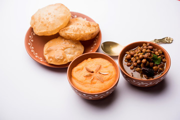 Suji/Sooji Halwa Puri or Shira Poori with black chana masala breakfast, served in a plate and bowl. selective focus