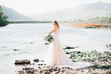Portrait of stunning bride with long hair standing by the river