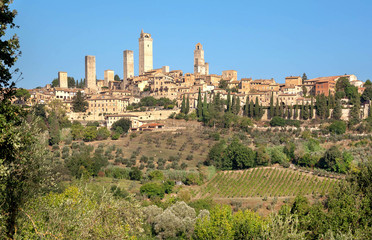 Fototapeta na wymiar Towers and traditional brick houses of ancient Tuscan town at sunny day. Historic San Gimignano town. UNESCO World Heritage Site