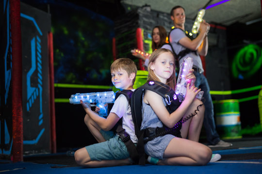Kids sitting back to back with laser guns