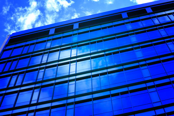  Modern glass architecture with reflection of white and blue sunset sky.