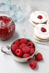 Bowl with raspberries, homemade cookies and jar of jam.
