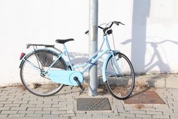 Vintage bicycle, for women. Leaning on the light pole.