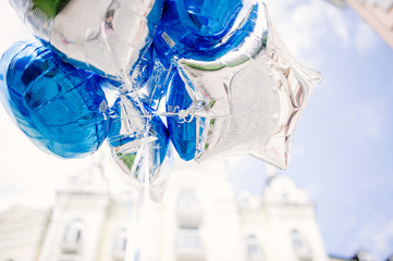festive bundle of bright blue and silver balloons against a blue sky background