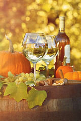 Glasses of white wine with pumpkins on barrel