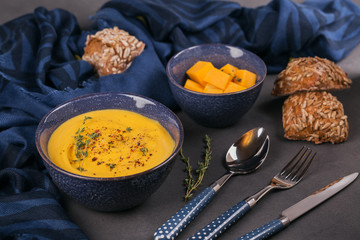 Pumpkin soup in blue bowl topped with fresh herb