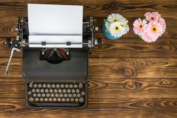 Overhead view of typewriter next to flowers