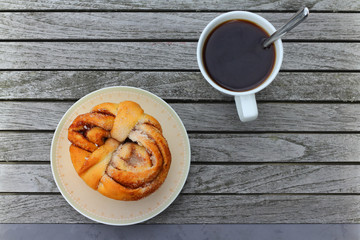 Cup of coffee and bun with cinnamon