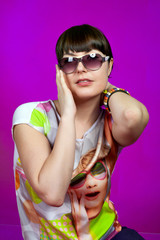 Fashion girn in pop disco pin up style in black sunglasses on purple background in studio