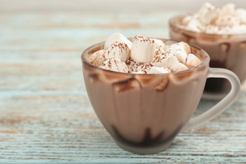 Cup of chocolate milk with marshmallows on light wooden table, closeup