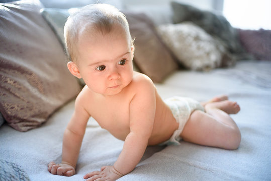 Cute baby girl on belly on couch in diaper