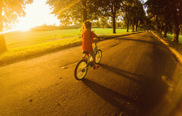 Little girl with riding bike at sunset