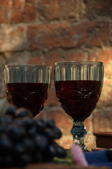Naklejka na ściany i meble Two glasses of wine against a brick wall.