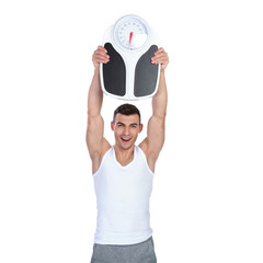 fit young man celebrating weight loss while holding scale