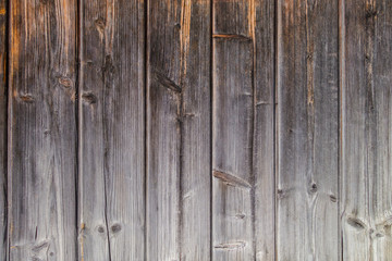 fragment of the old country house of natural wooden timbers without coloring. Gray-brown wooden background. vertical wooden stripes.