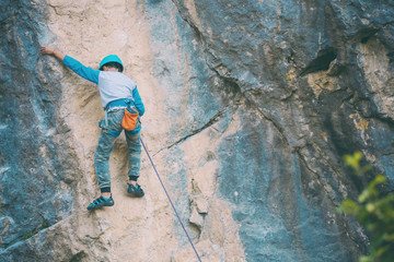 A child climber climbs on a rock.