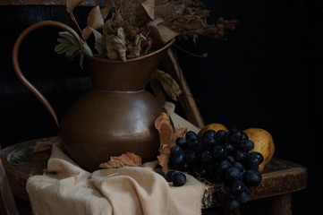 Still life with dry bouquet in a copper jug and fruits.