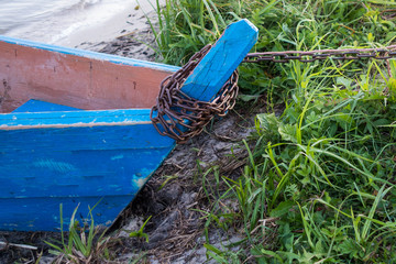 Nose of wooden old blue boat, close-up view from the nose, stands on the green grass, tethered metal chain