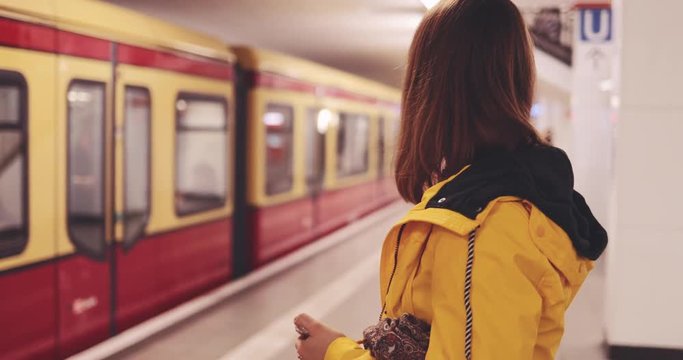 Young Woman Using Smartphone at the Train Station. SLOW MOTION 4K. Girl using cell phone, waiting for subway train. Social network, planning, communicating.