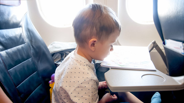 Toned image of little boy sitting in airplane passenger seat