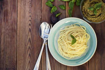 Italian traditional spaghetti with basil pesto pasta with cheese, pine nuts, olive oil, rustic table. Copy space.