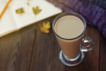 Diary, cup of hot cocoa, warm scarf and autumn leaves on a wooden background Copy sapce. Cozy. Autumn concept.