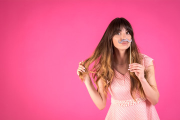 Girl with a funny black mustache. Festive decor.