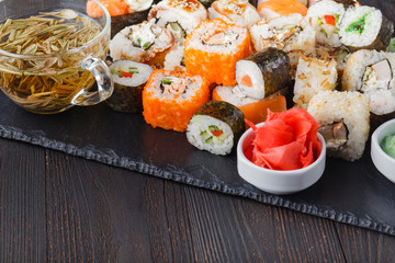 Pile of Various kinds of sushi served on black stone