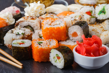 Sushi rolls, maki, nigiri Set served for two on black stone slate on dark background