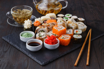 Fototapeta na wymiar Sushi rolls, maki, nigiri Set served for two on black stone slate on dark background