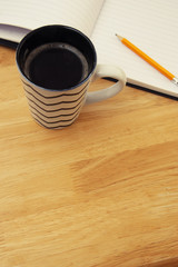 Work space. Open notebook with cup of coffee on wooden desk. Copy space.