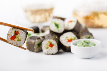 Female hand holding wooden sticks Philadelphia roll with salmon