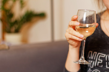 Young woman sitting barefoot on the sofa  and holding glass of white wine