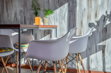 Close up of creative chairs, table and plant in a pot on grunge background.