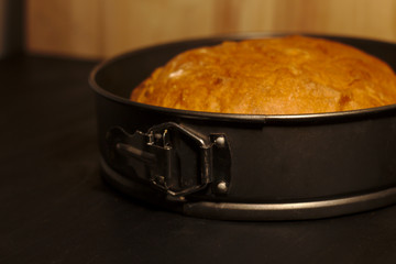 Freshly baked homemade bread in a round baking dish on a dark background