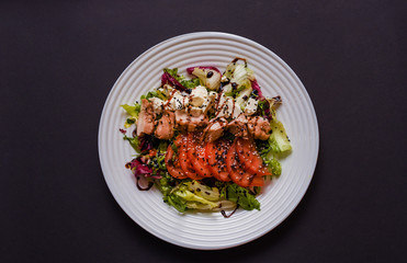 Meat salad with tomato served in white plate on dark table. Copy space