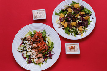 Meat salad with tomato served in white plate on dark table. Copy space
