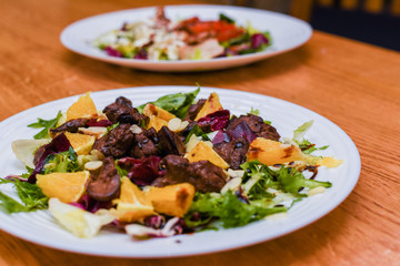 Meat salad with tomato served in white plate on dark table. Copy space
