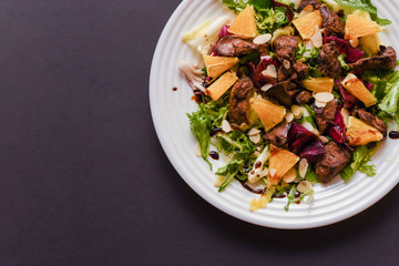 Meat salad with tomato served in white plate on dark table. Copy space