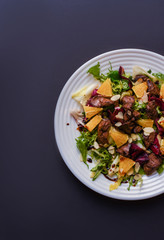 Meat salad with tomato served in white plate on dark table. Copy space