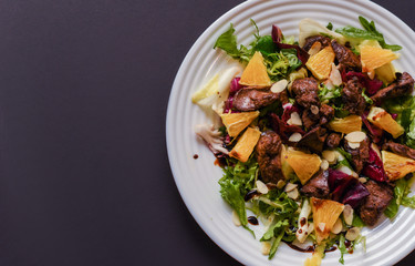 Meat salad with tomato served in white plate on dark table. Copy space