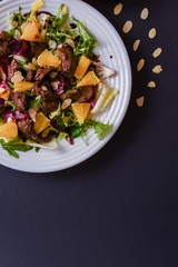 Meat salad with tomato served in white plate on dark table. Copy space