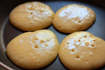 Four pancakes are cooked on a frying pan