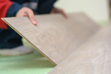 Happy young woman measuring and marking laminate floor tile, installing laminate flooring. Close-up...
