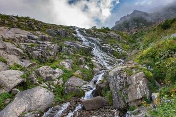 Caucasus mountain waterfall on rock mountain in the green rocky mountainside.
