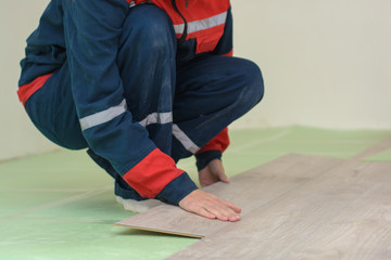 Happy young woman measuring and marking laminate floor tile, installing laminate flooring. Close-up...