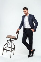 Well dressed and confident. Full length of handsome young man looking at camera while standing against white background