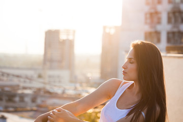pretty city girl profile portrait at sunset backlight at top of building