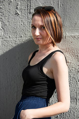 young girl posing against a concrete wall, dressed in black, hard light and shadows