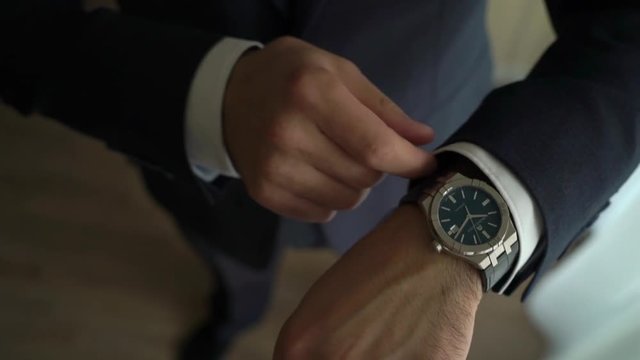 Businessman checking time on his wrist watch, man putting clock on hand, groom getting ready in the morning before wedding ceremony unrecognizable